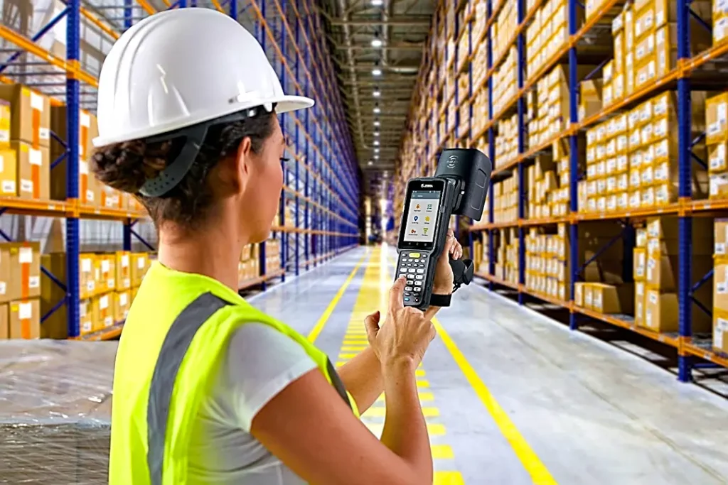 consultoria industrial, aprovisionamento, uma operadora scaneando códigos de barras num armazém industrial